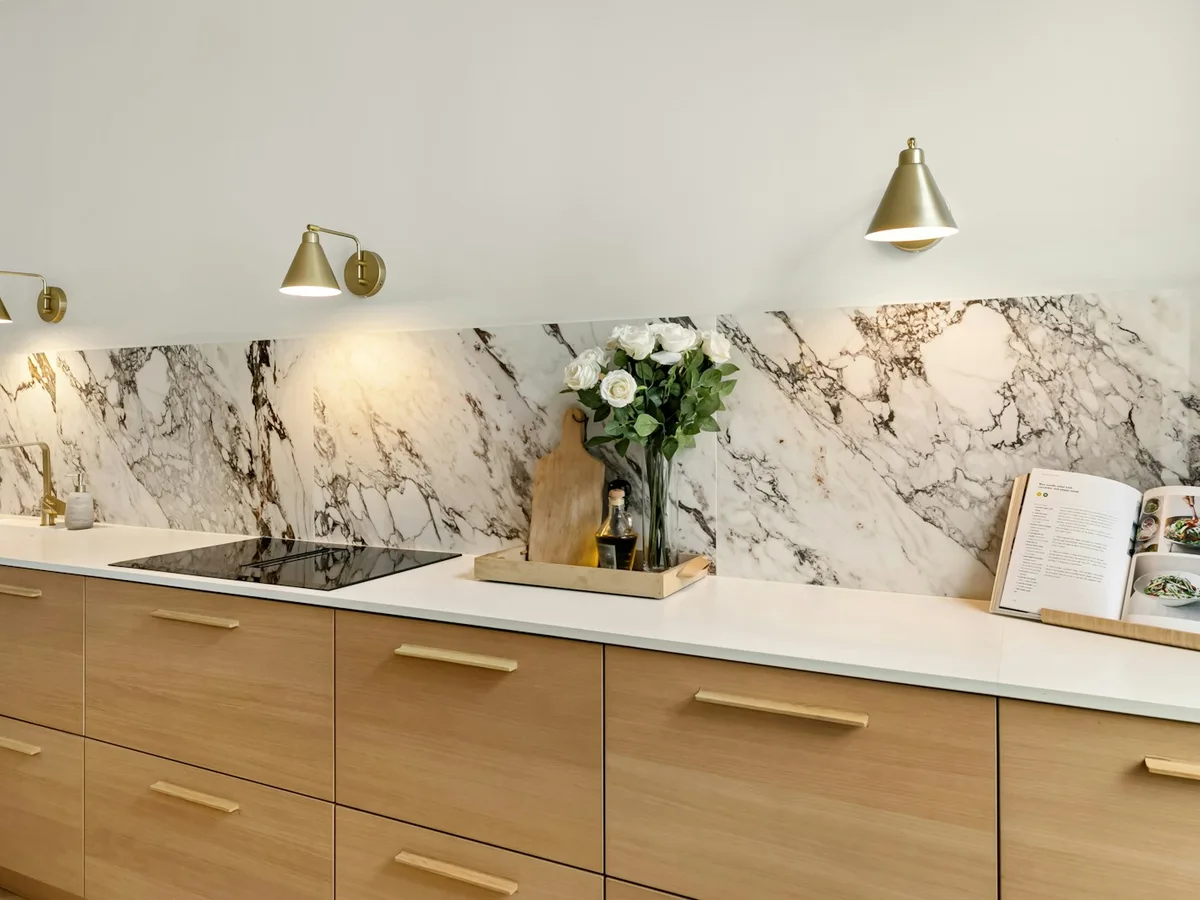 Cucina finita con top chiaro, legno e rivestimento marmo
