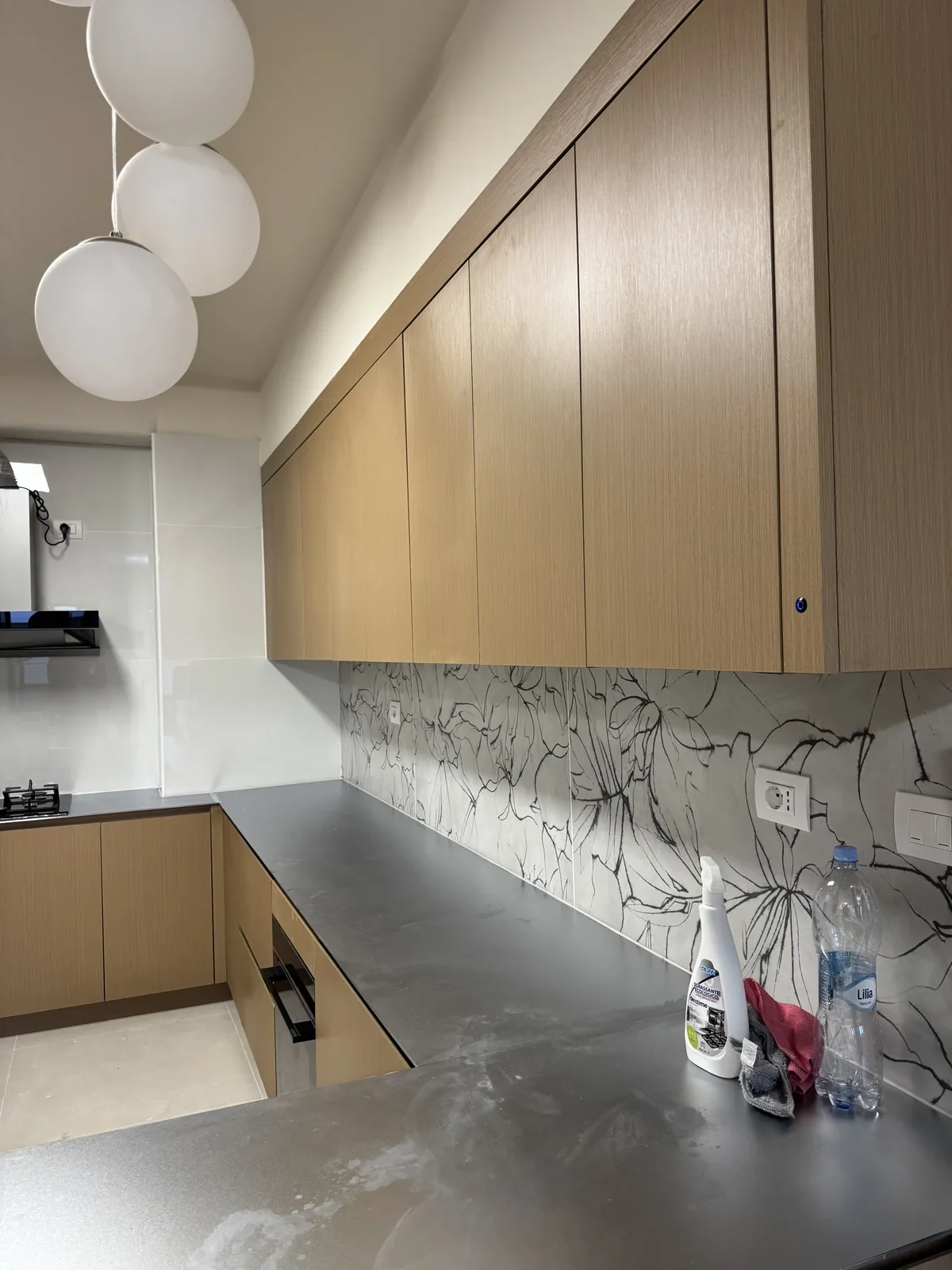 Cucina del progetto Mantova con mobili in legno, piano metallico e rivestimento floreale